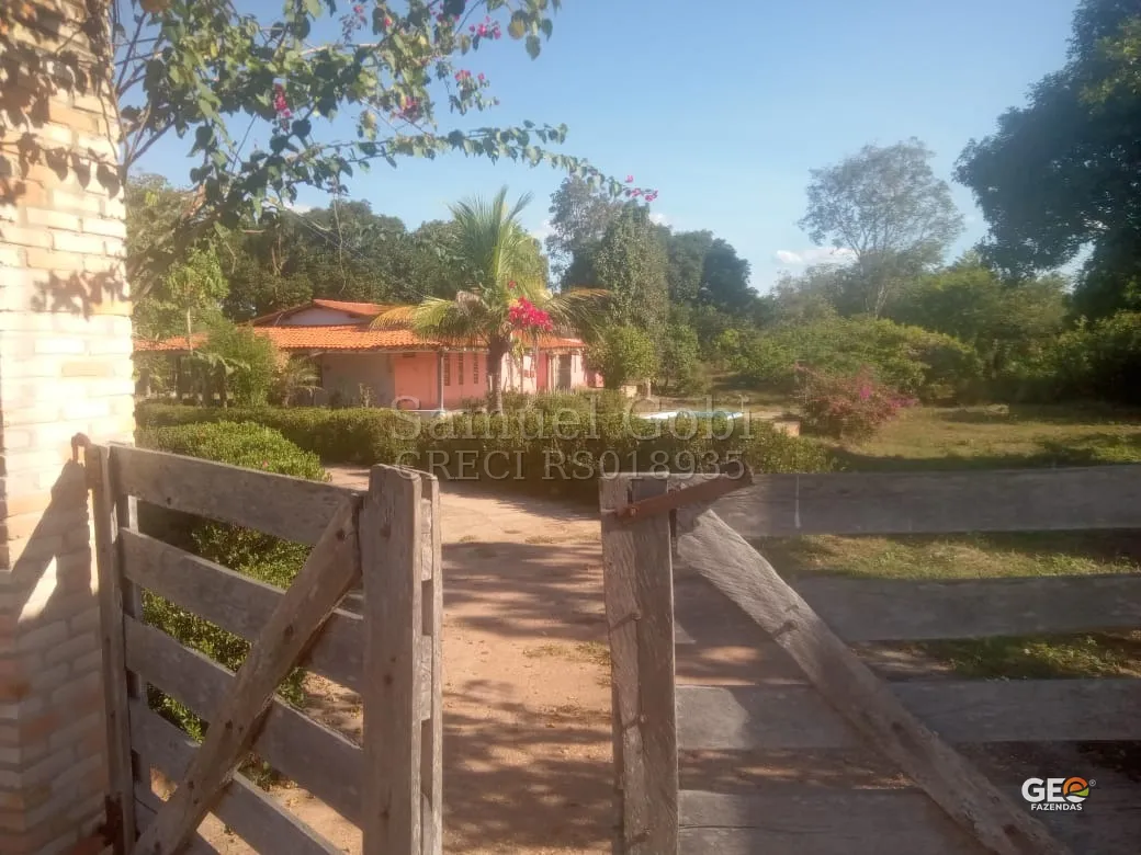Entrada com cerca de madeira e casa rural