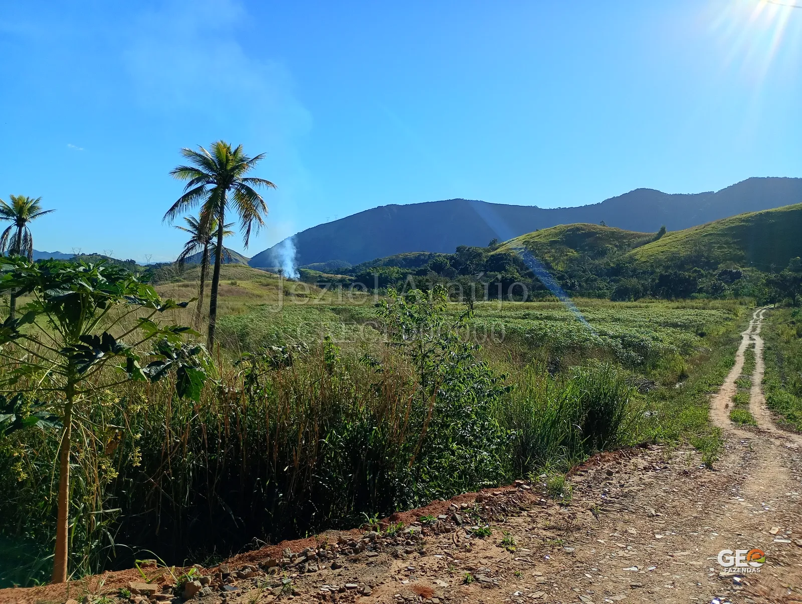 Área rural com estrada de terra e montanhas