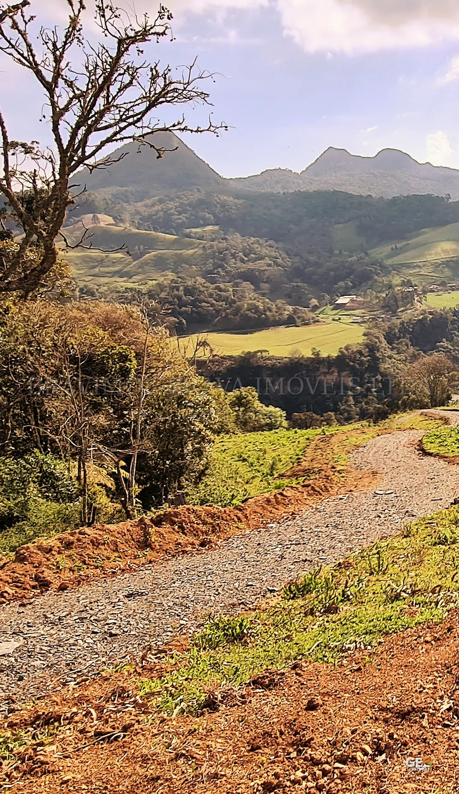 Estrada de terra em área rural com montanhas ao fundo