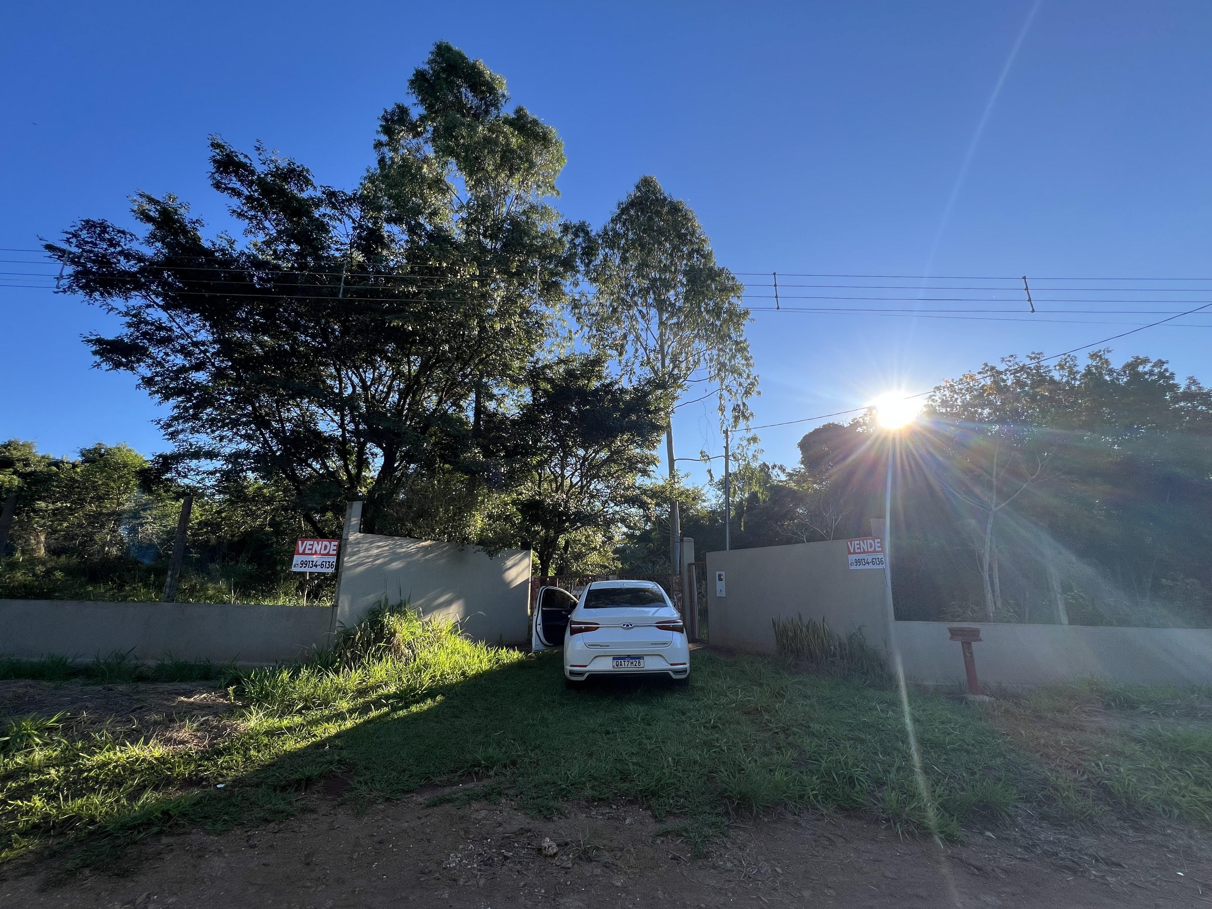 Entrada de propriedade rural com carro e muro